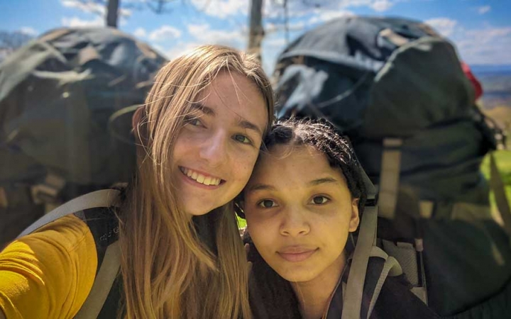 two girls wearing backpacks smile on an outward bound trip near DC